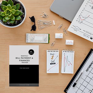 A desk with a laptop, calculator, and a pen surrounded by various financial documents and a potted p