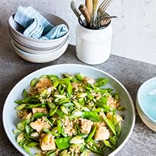 large bowl of chicken with brown rice & snow peas, on a table with an empty blue bowl.