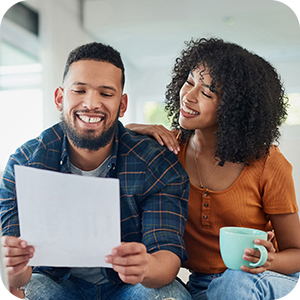 couple holding a sheet of paper and cup of tea