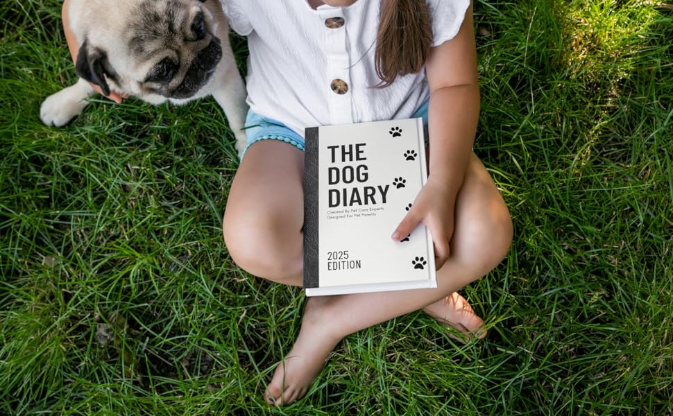 Dog Pug and child sitting on green grass holding book Dog Diary