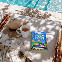 Hardback book on lounger by pool with sun glasses, hat and teacup
